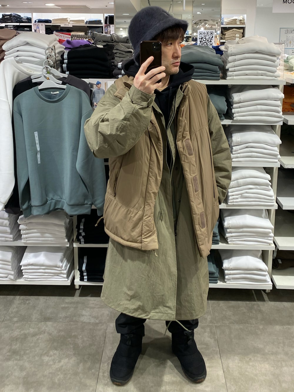 ブラウン系のダウンベスト、グリーン系のモッズコート、ブラック系のブーツを着用したメンズの冬コーディネートの2枚目の写真