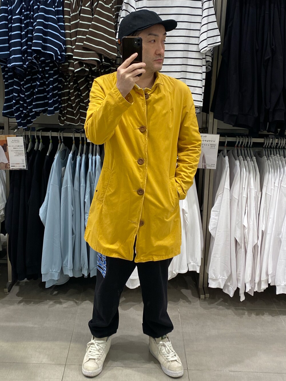 イエロー系のステンカラーコート、ブラック系のスウェットパンツ、ホワイト系のスニーカーを着用したメンズの春コーディネートの4枚目の写真