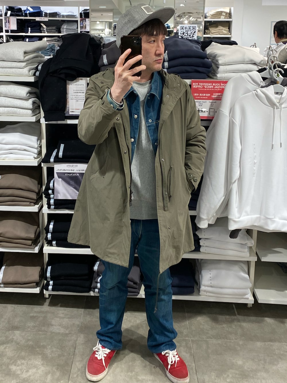 グリーン系のモッズコート、ブルー系のデニムパンツ、レッド系のスニーカーを着用したメンズの春コーディネートの2枚目の写真