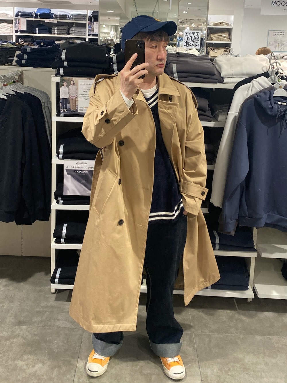 ベージュ系のトレンチコート、ブルー系のカーゴパンツ、オレンジ系のスニーカーを着用したメンズの春コーディネートの2枚目の写真
