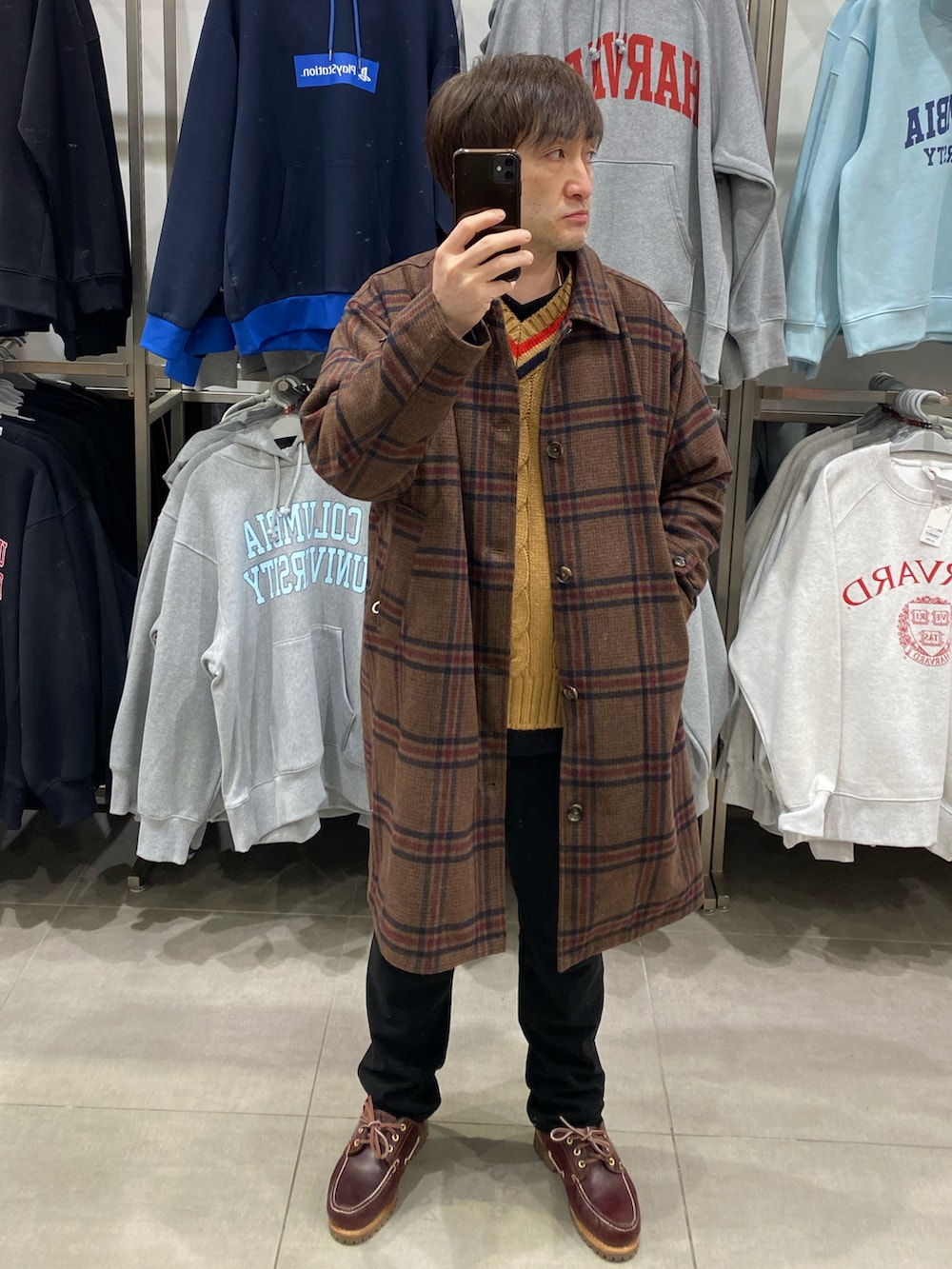 ブラウン系のステンカラーコート、ブラウン系のモカシン/デッキシューズ、ブラウン系のニット/セーターを着用したメンズの冬コーディネートの4枚目の写真