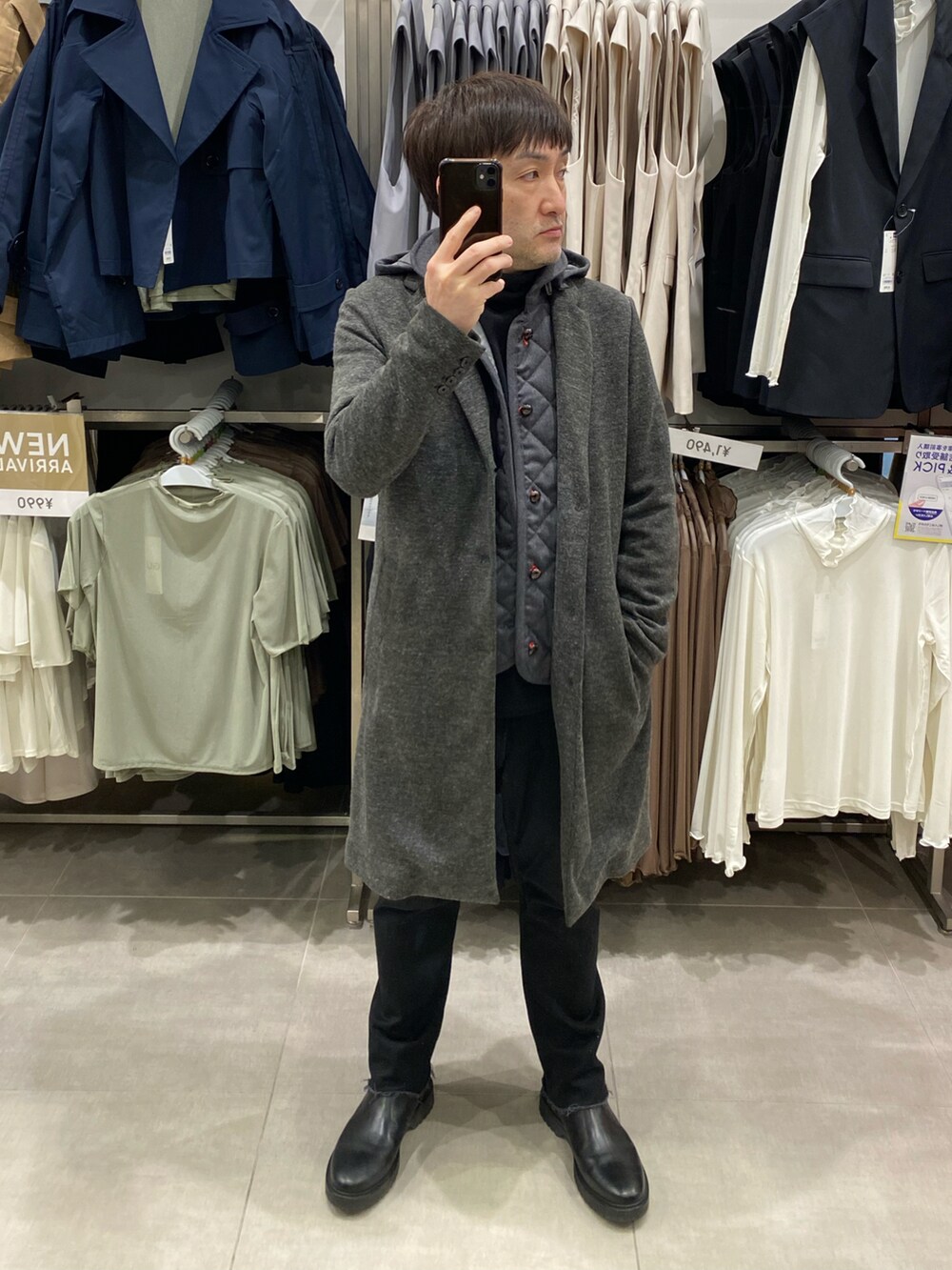 グレー系のチェスターコート、ブラック系のデニムパンツ、ブラック系のブーツを着用したメンズの春コーディネートの3枚目の写真