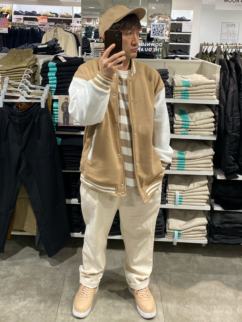 ベージュ系のスタジャン、ホワイト系のスラックス、ベージュ系のスニーカーを着用したメンズの秋コーディネートの2枚目の写真