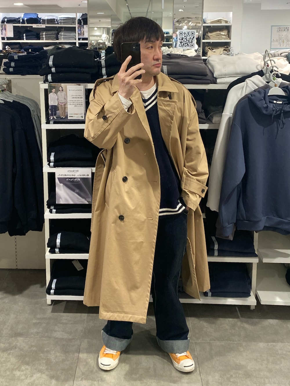 ベージュ系のトレンチコート、ブルー系のカーゴパンツ、オレンジ系のスニーカーを着用したメンズの春コーディネートの3枚目の写真