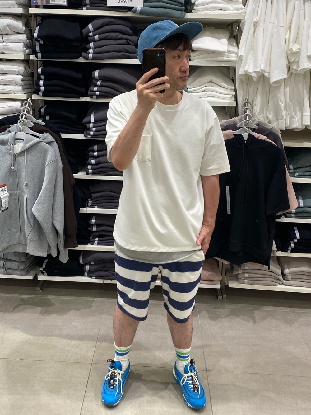 ホワイト系のポロシャツ、ブルー系のスニーカー、ブルー系のキャップを着用したメンズの夏コーディネートの2枚目の写真