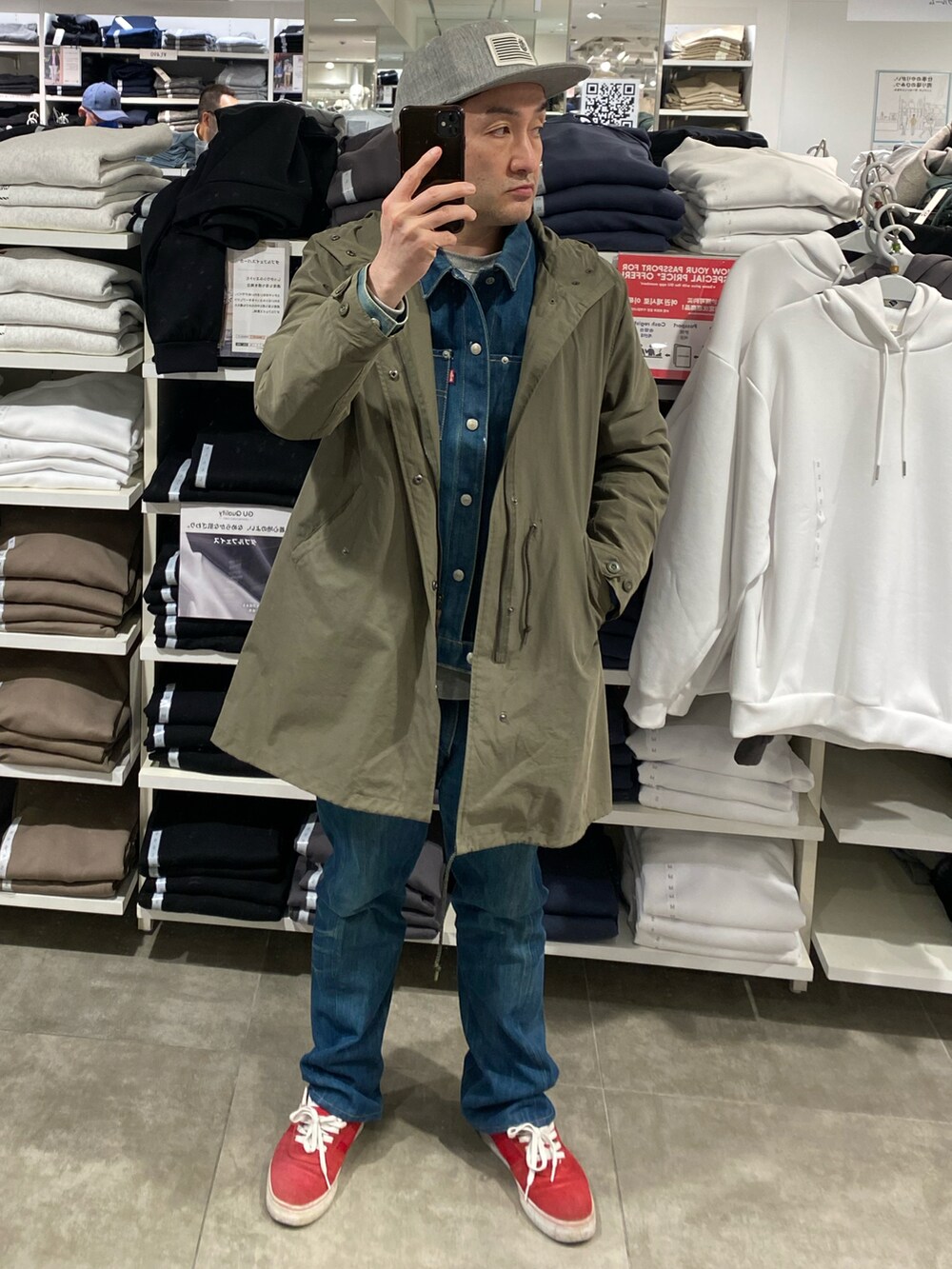 グリーン系のモッズコート、ブルー系のデニムパンツ、レッド系のスニーカーを着用したメンズの春コーディネートの4枚目の写真