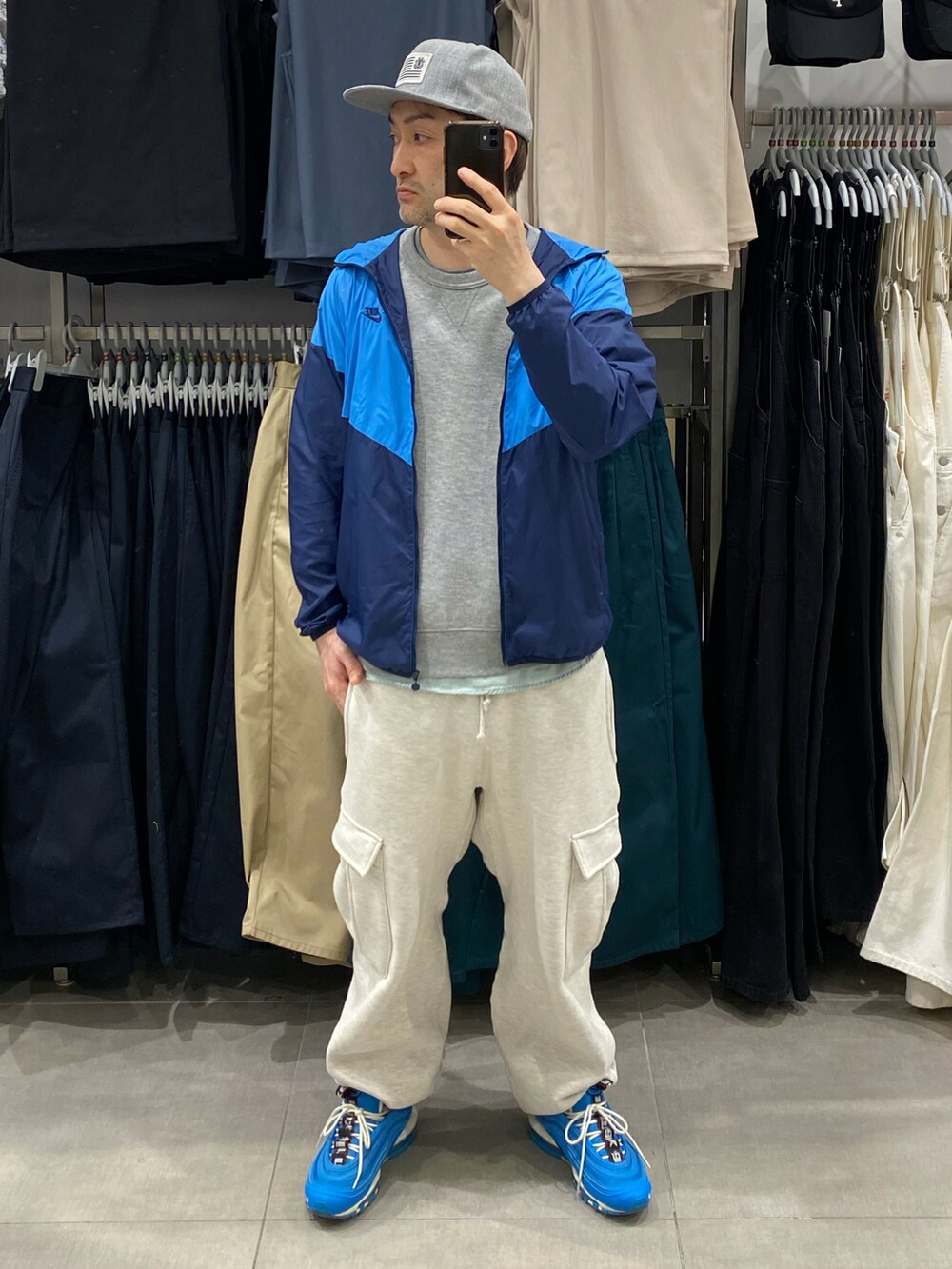 ブルー系のナイロンジャケット、グレー系のカーゴパンツ、ブルー系のスニーカーを着用したメンズの春コーディネートの3枚目の写真