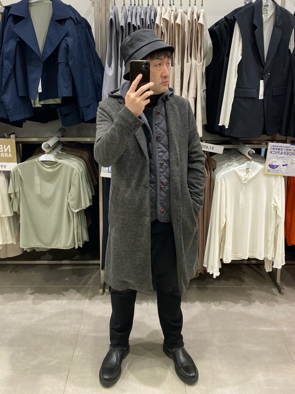 グレー系のチェスターコート、ブラック系のデニムパンツ、ブラック系のブーツを着用したメンズの春コーディネートの2枚目の写真