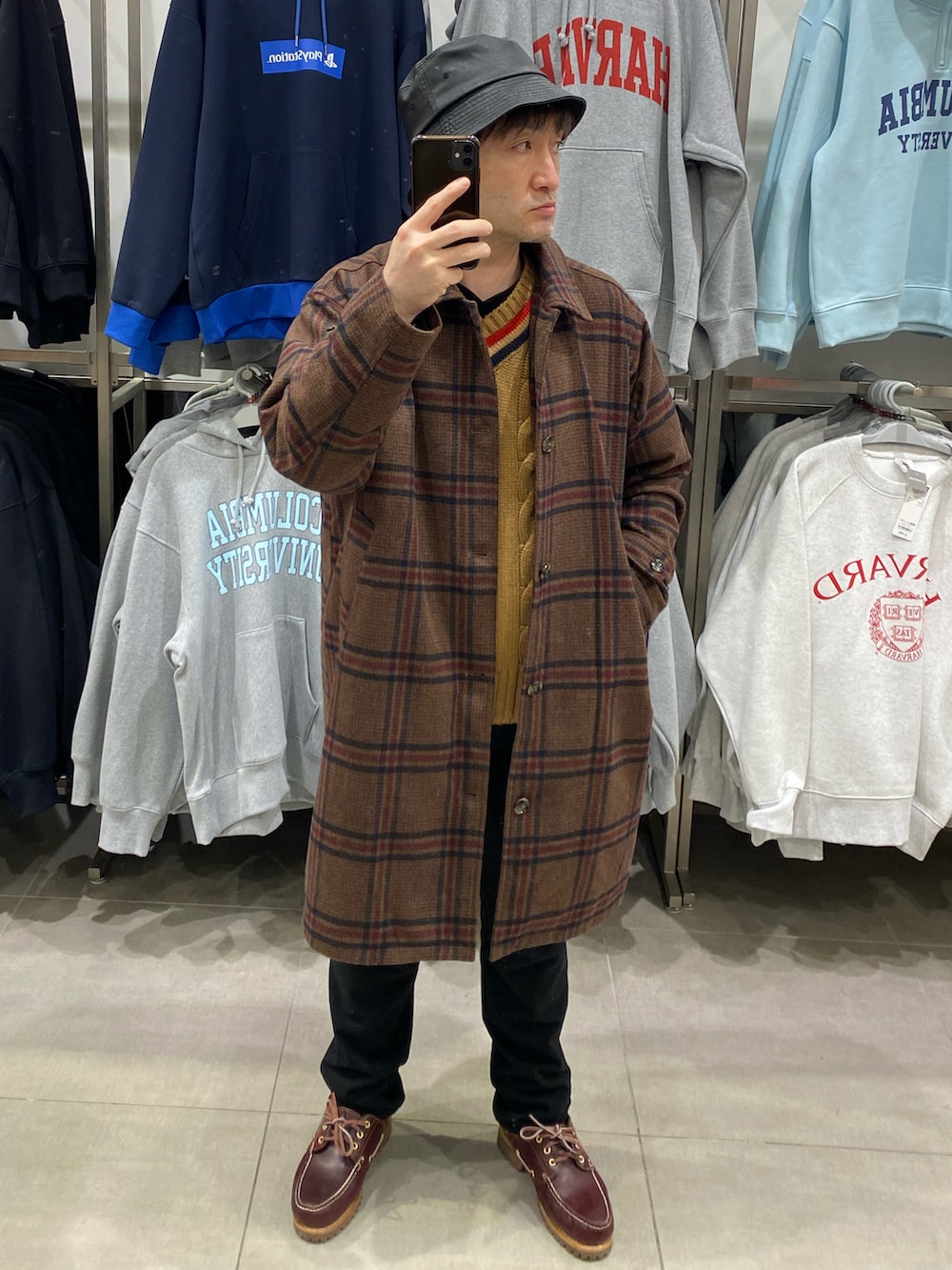 ブラウン系のステンカラーコート、ブラウン系のモカシン/デッキシューズ、ブラウン系のニット/セーターを着用したメンズの冬コーディネートの3枚目の写真