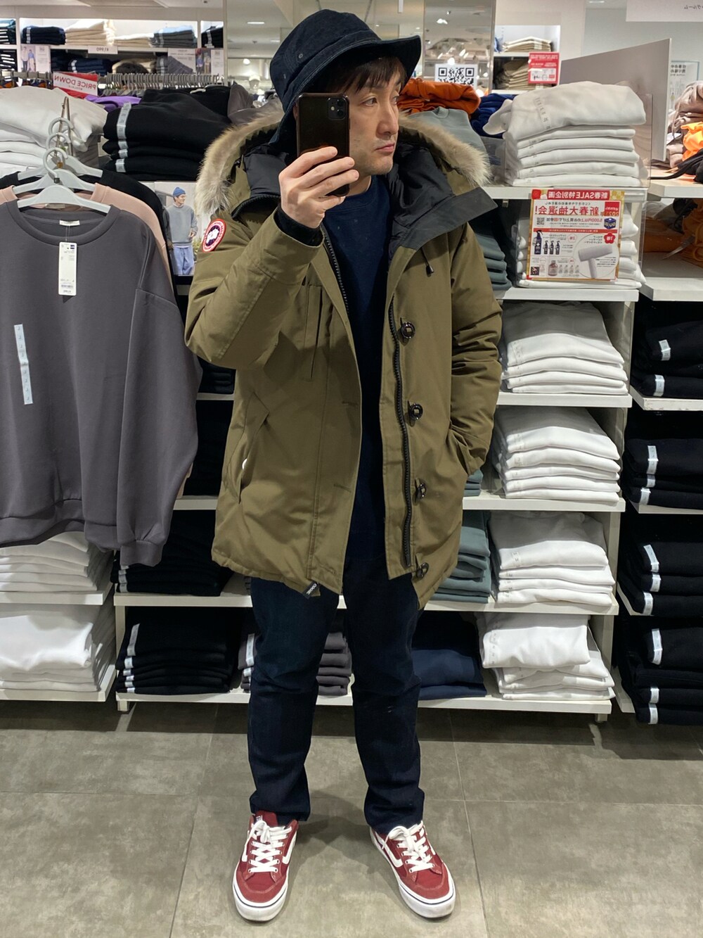 グリーン系のダウンジャケット/コート、ブルー系のデニムパンツ、レッド系のスニーカーを着用したメンズの冬コーディネートの2枚目の写真