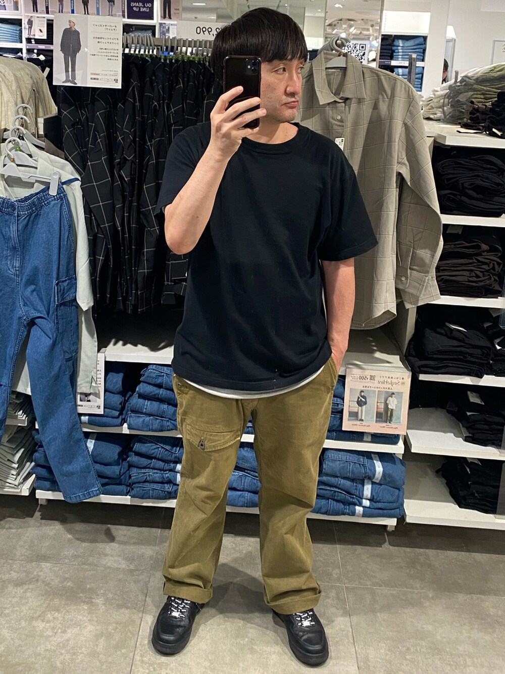 グリーン系のカーゴパンツ、ブラック系のTシャツ/カットソー、ブラック系のスニーカーを着用したメンズの秋コーディネートの3枚目の写真