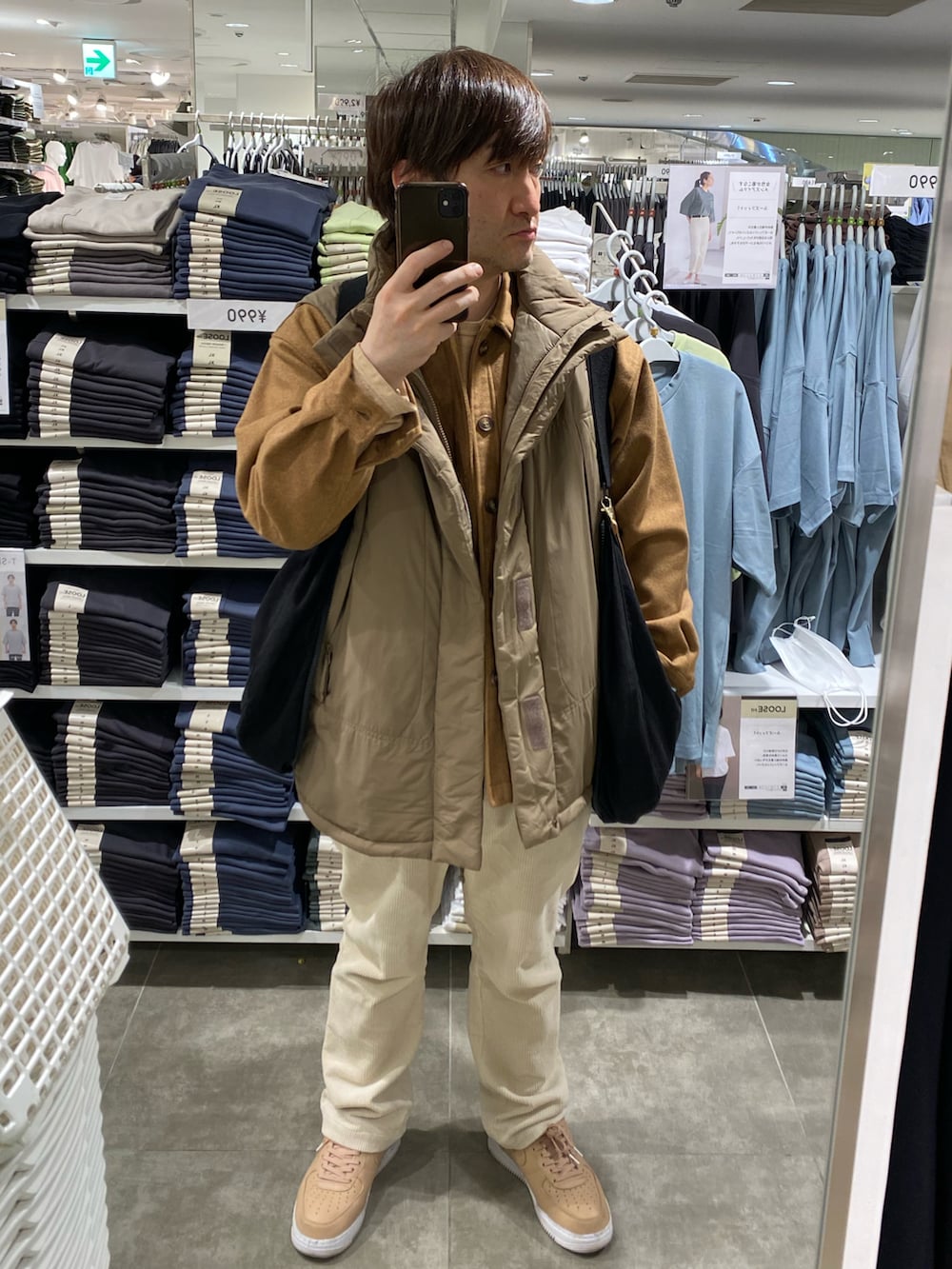 ブラック系のショルダーバッグ、イエロー系のカバーオール、ブラウン系のダウンベストを着用したメンズの春コーディネートの5枚目の写真