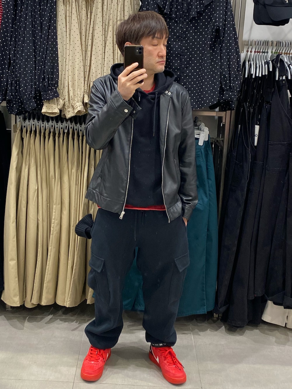 ブラック系のライダースジャケット、ブラック系のパーカー、ブラック系のカーゴパンツを着用したメンズの春コーディネートの3枚目の写真