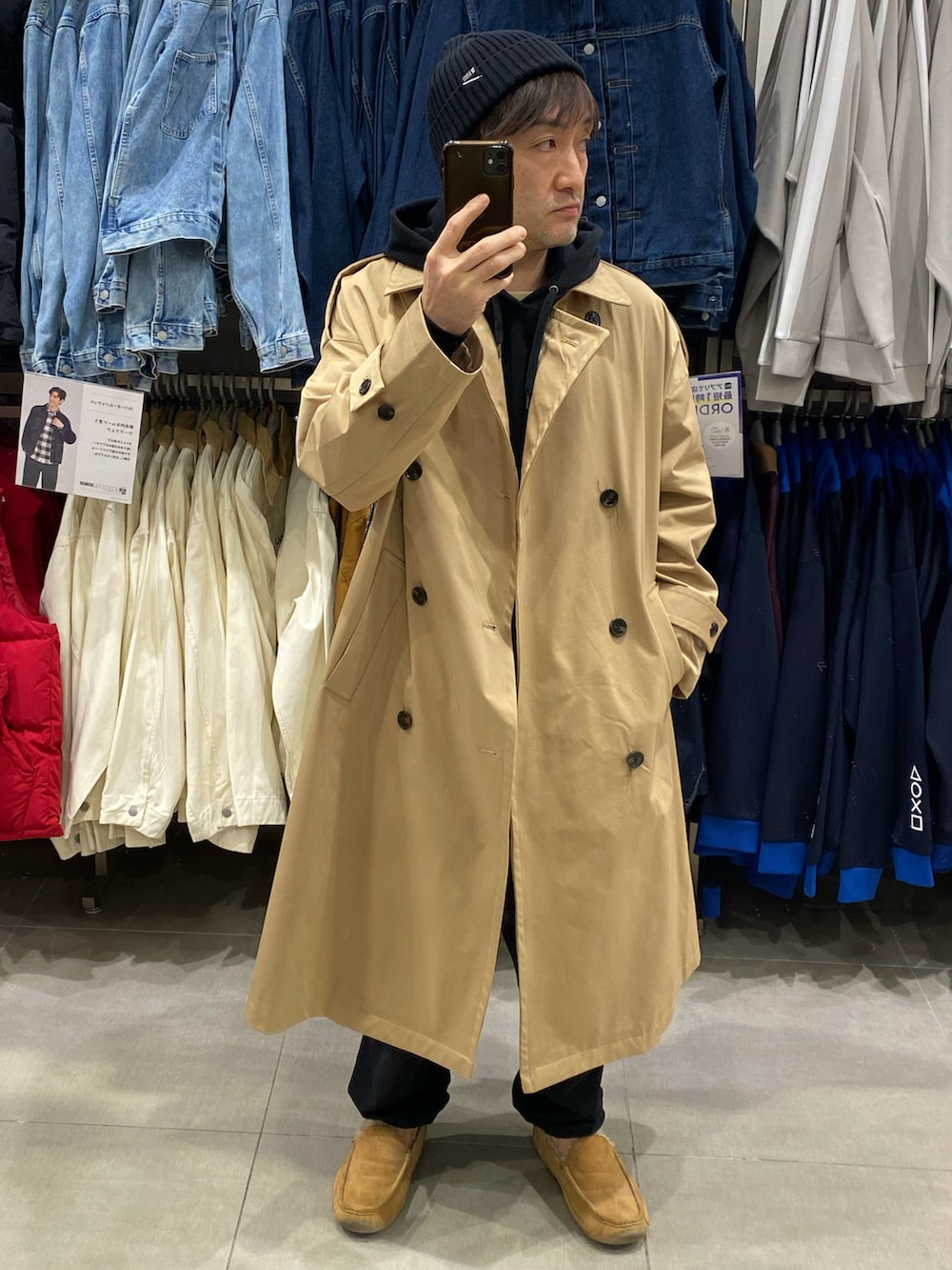 ブラック系のパーカー、ベージュ系のトレンチコート、ベージュ系のモカシン/デッキシューズを着用したメンズの秋コーディネートの2枚目の写真