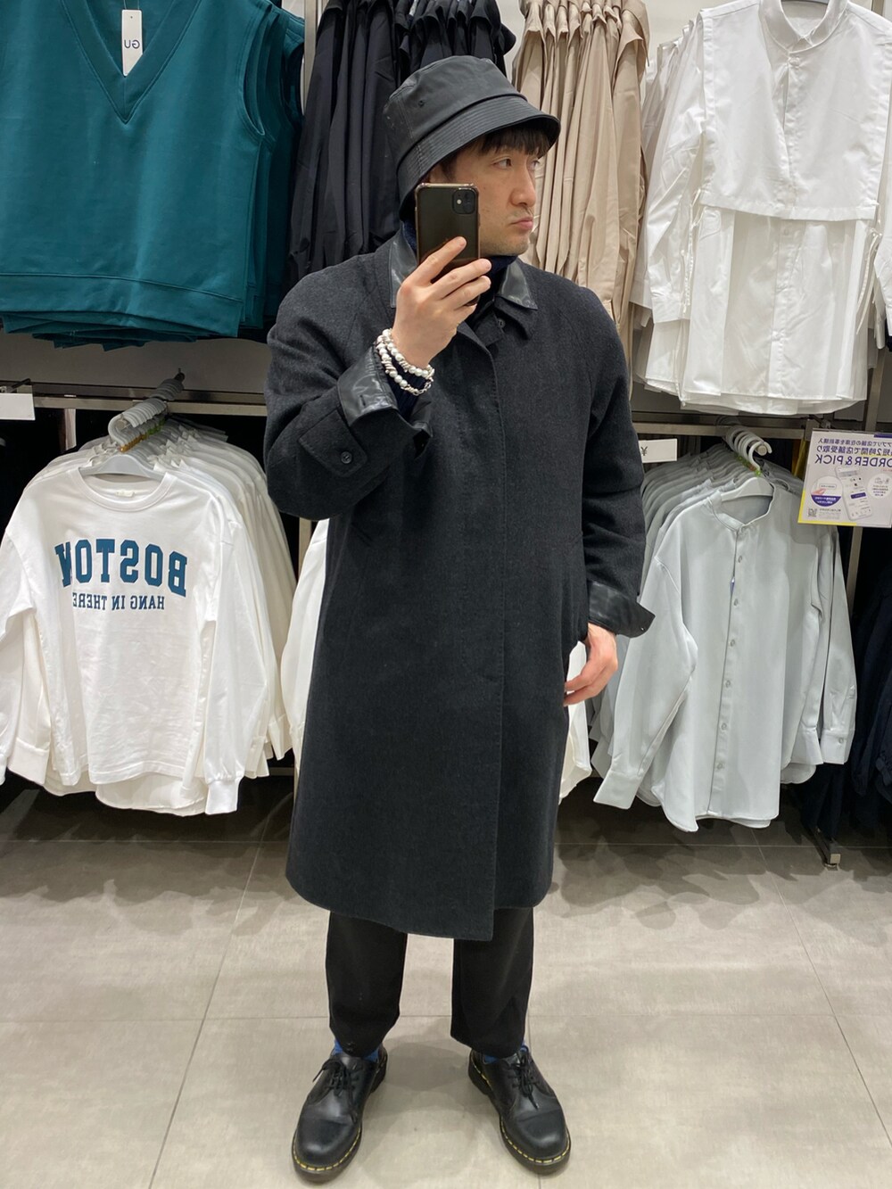 グレー系のステンカラーコート、ブラック系のスウェットパンツ、ブラック系のドレスシューズを着用したメンズの冬コーディネートの3枚目の写真