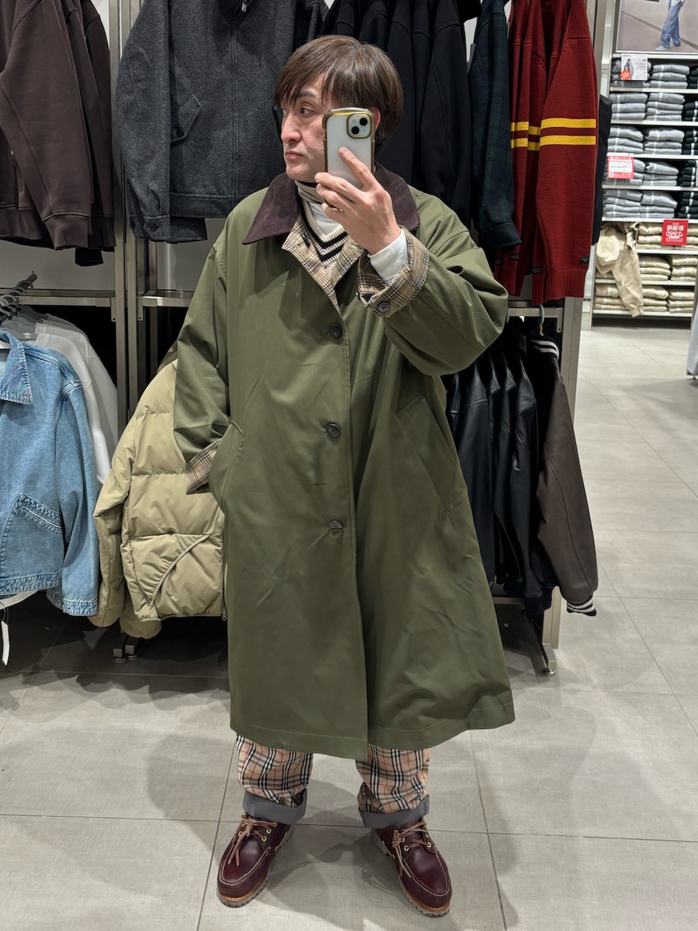 グリーン系のステンカラーコート、ブラウン系のモカシン/デッキシューズ、ベージュ系のベストを着用したメンズの冬コーディネートの2枚目の写真
