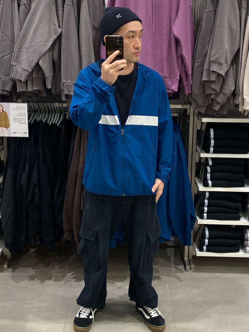 ブルー系のナイロンジャケット、ブラック系のカーゴパンツ、ブラック系のスニーカーを着用したメンズの秋コーディネートの2枚目の写真