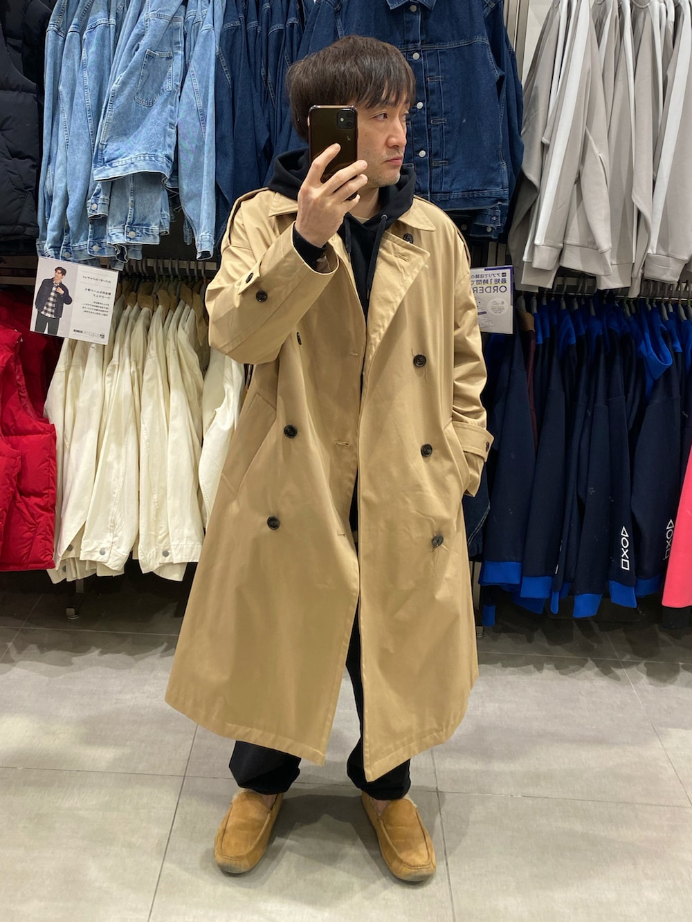 ブラック系のパーカー、ベージュ系のトレンチコート、ベージュ系のモカシン/デッキシューズを着用したメンズの秋コーディネートの3枚目の写真