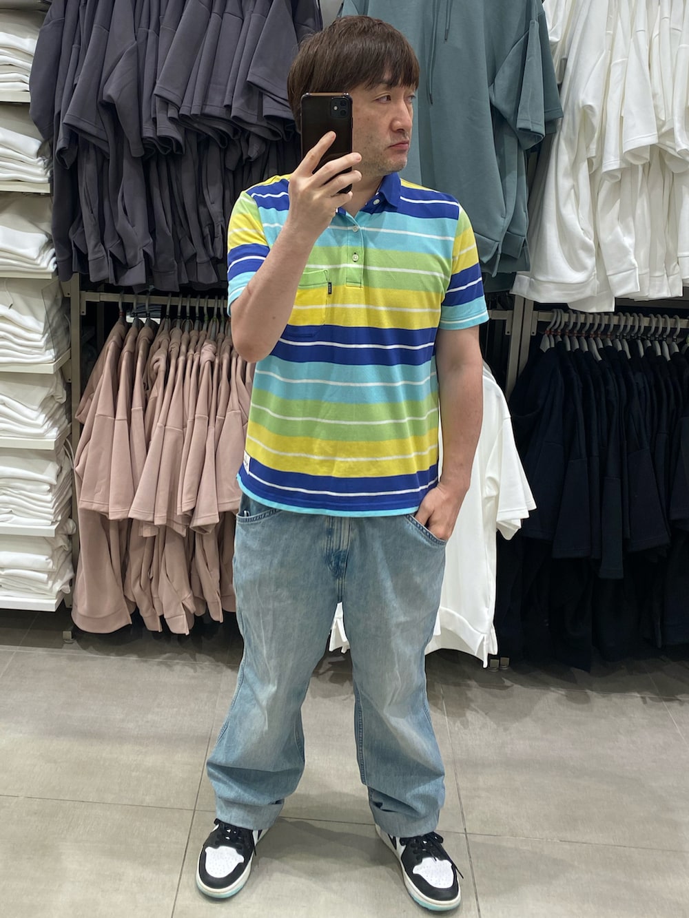 ブルー系のデニムパンツ、ホワイト系のスニーカー、その他のポロシャツを着用したメンズの夏コーディネートの3枚目の写真