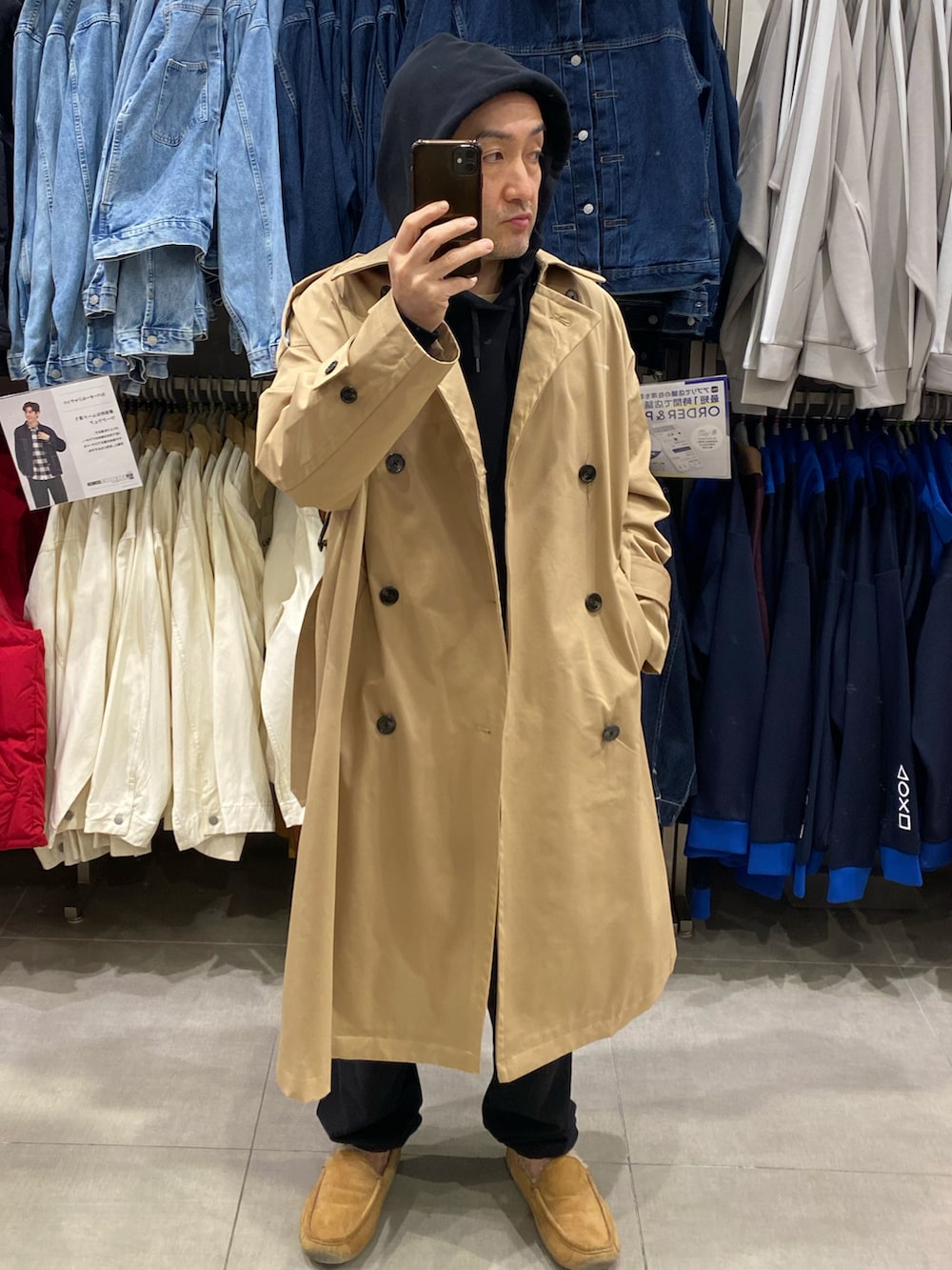 ブラック系のパーカー、ベージュ系のトレンチコート、ベージュ系のモカシン/デッキシューズを着用したメンズの秋コーディネートの5枚目の写真