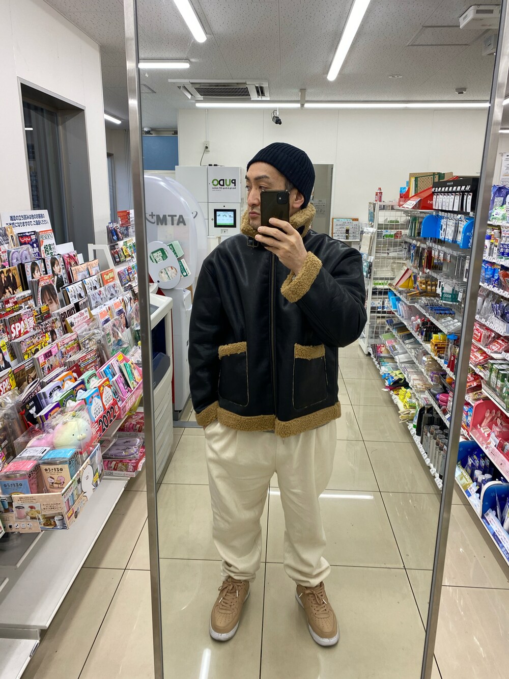 ブラック系のブルゾン、グレー系のスウェット、ホワイト系のスラックスを着用したメンズの冬コーディネートの2枚目の写真