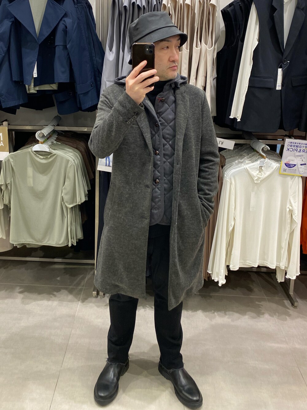 グレー系のチェスターコート、ブラック系のデニムパンツ、ブラック系のブーツを着用したメンズの春コーディネートの4枚目の写真