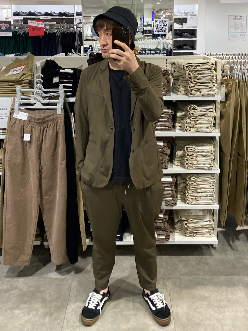 グリーン系のテーラードジャケット、グリーン系のスラックス、ブラック系のスニーカーを着用したメンズの秋コーディネートの3枚目の写真