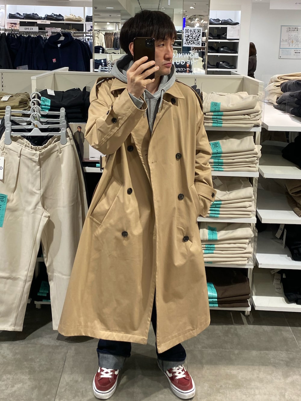 グレー系のパーカー、ベージュ系のトレンチコート、ブルー系のデニムパンツを着用したメンズの秋コーディネートの3枚目の写真