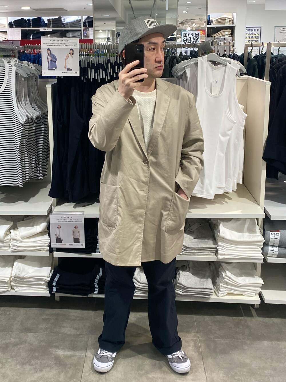 ベージュ系のチェスターコート、ブラック系のチノパンツ、グレー系のスニーカーを着用したメンズの春コーディネートの4枚目の写真