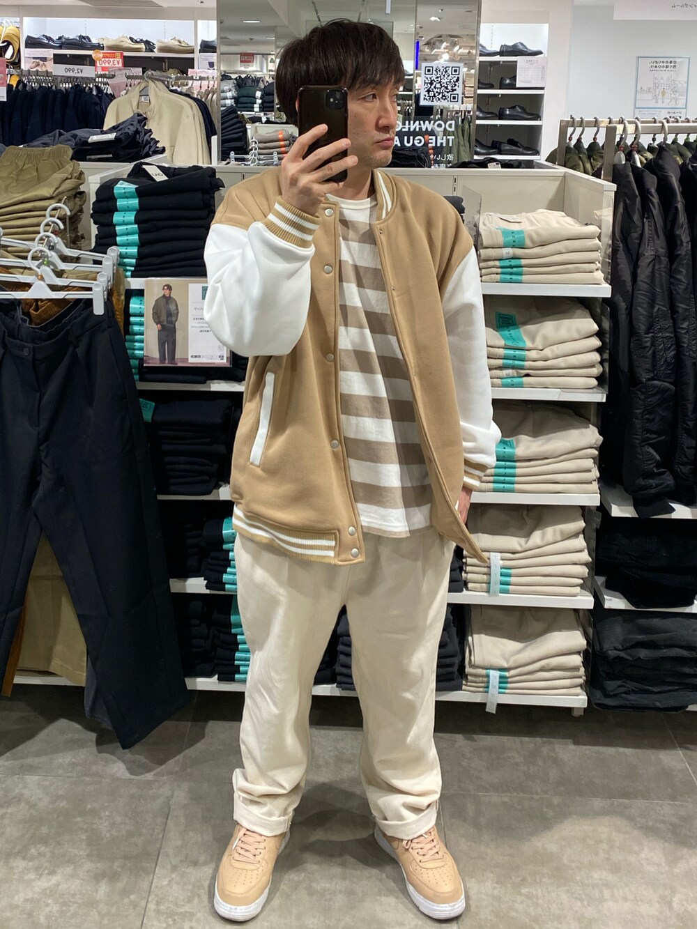 ベージュ系のスタジャン、ホワイト系のスラックス、ベージュ系のスニーカーを着用したメンズの秋コーディネートの3枚目の写真