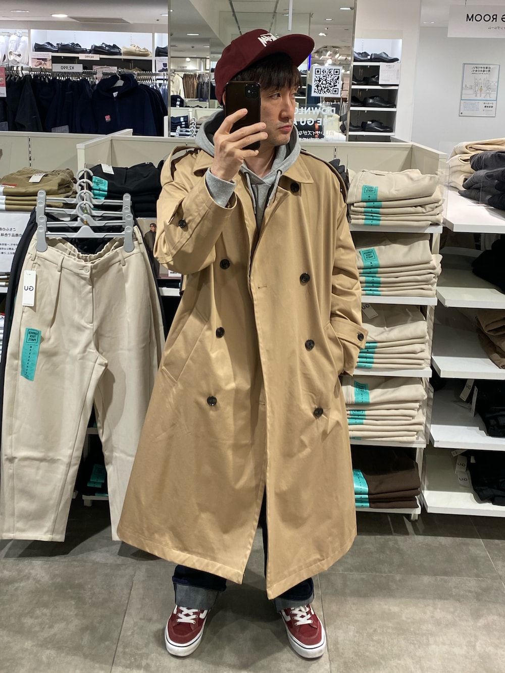 グレー系のパーカー、ベージュ系のトレンチコート、ブルー系のデニムパンツを着用したメンズの秋コーディネートの2枚目の写真