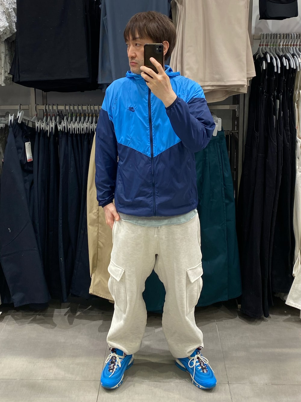 ブルー系のナイロンジャケット、グレー系のカーゴパンツ、ブルー系のスニーカーを着用したメンズの春コーディネートの5枚目の写真