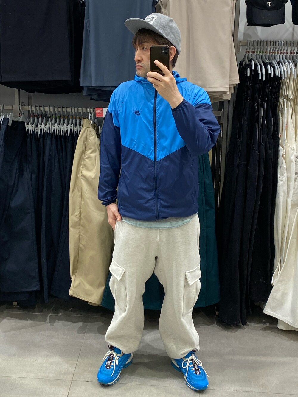 ブルー系のナイロンジャケット、グレー系のカーゴパンツ、ブルー系のスニーカーを着用したメンズの春コーディネートの4枚目の写真