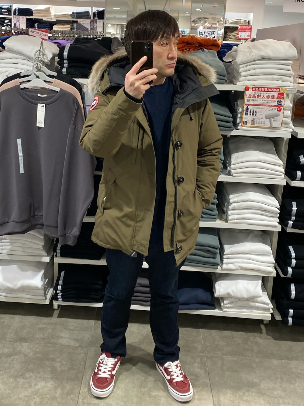 グリーン系のダウンジャケット/コート、ブルー系のデニムパンツ、レッド系のスニーカーを着用したメンズの冬コーディネートの3枚目の写真