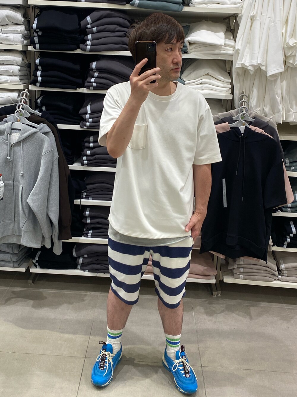 ホワイト系のポロシャツ、ブルー系のスニーカー、ブルー系のキャップを着用したメンズの夏コーディネートの3枚目の写真