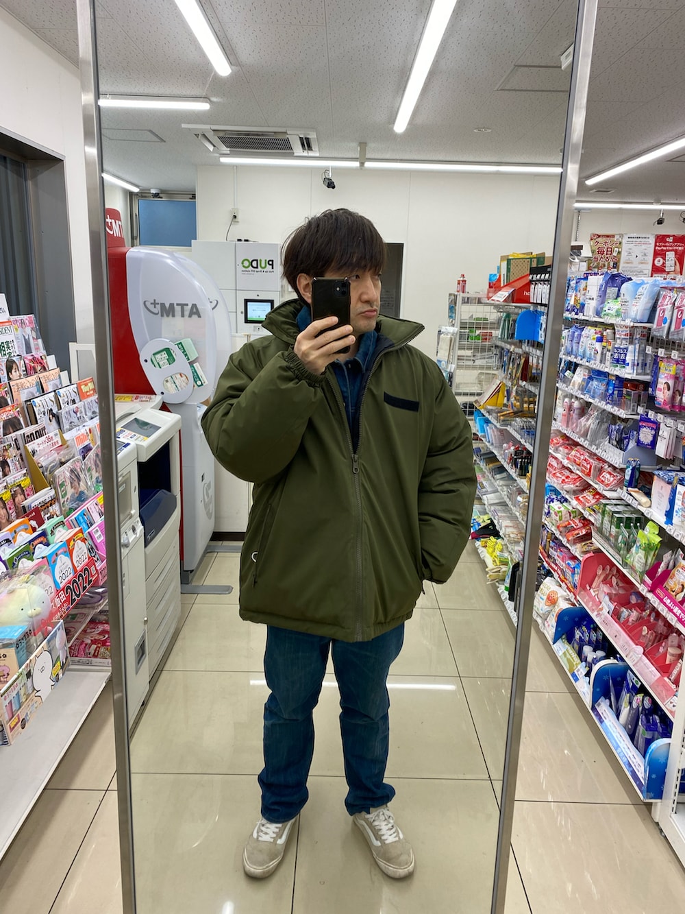 グレー系のカバーオール、ブルー系のデニムパンツ、ベージュ系のスニーカーを着用したメンズの冬コーディネートの3枚目の写真