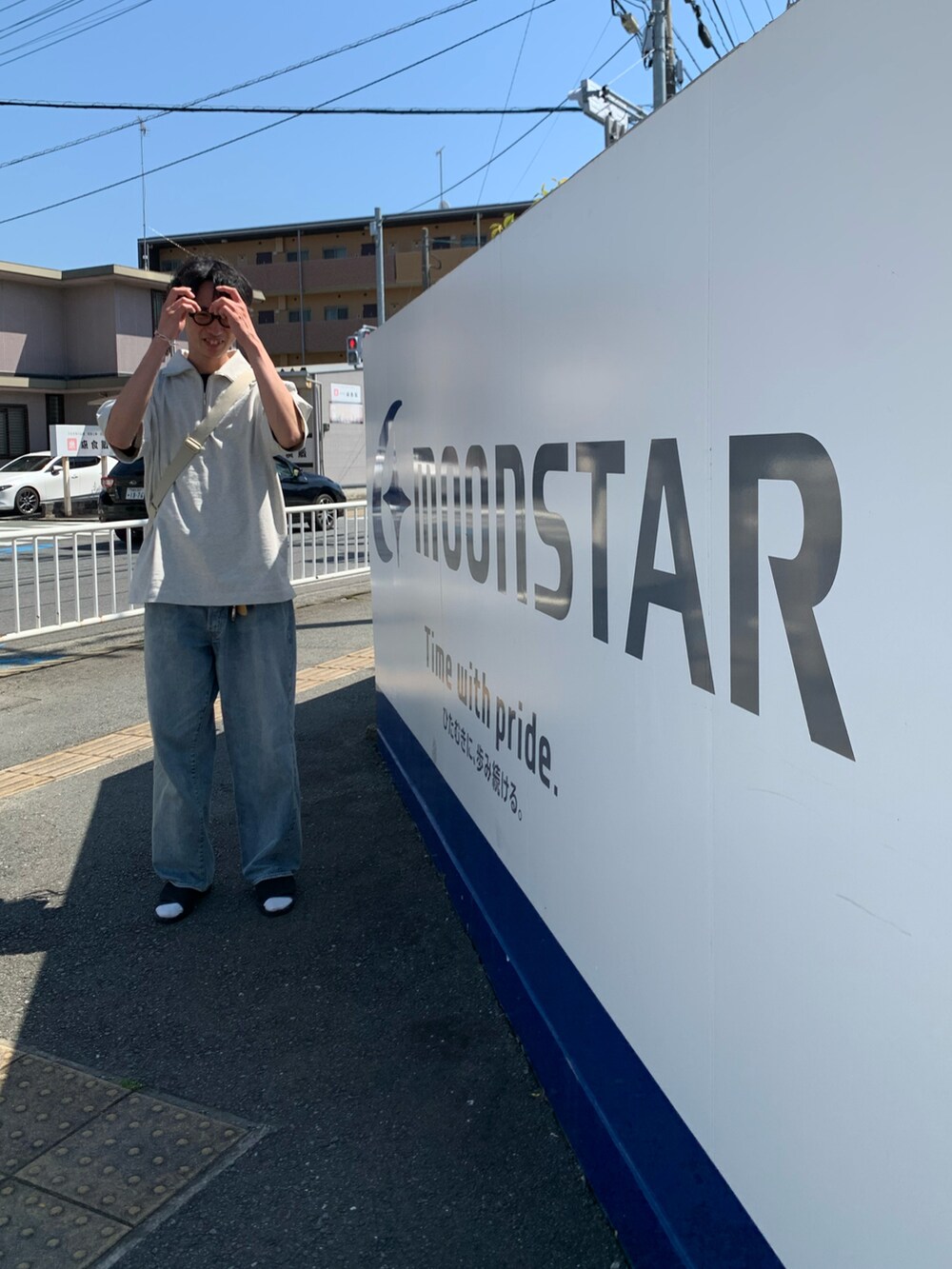 ホワイト系のトップス、ブルー系のデニムパンツ、ブラック系のサンダルを着用したメンズの春コーディネートの2枚目の写真