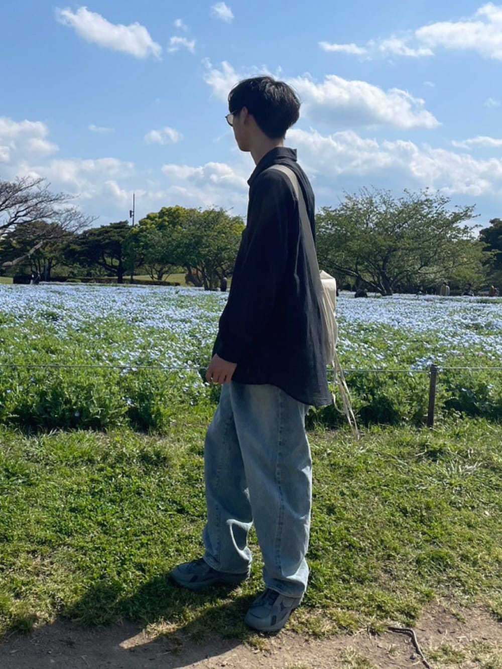 ブラック系のシャツ/ブラウス、グレー系のスニーカー、ブルー系のデニムパンツを着用したメンズの春コーディネートの2枚目の写真