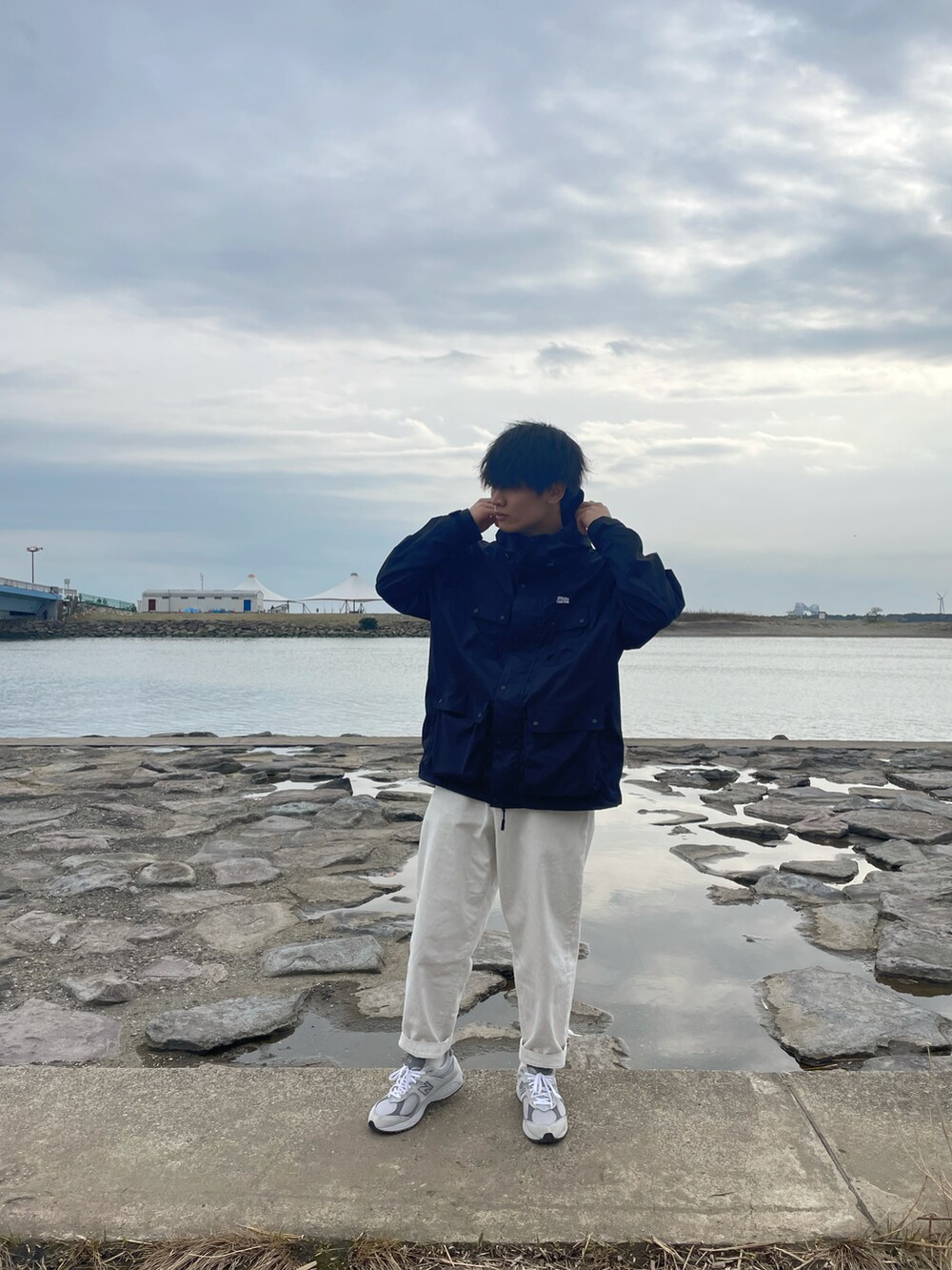 ブラック系のナイロンジャケット、ホワイト系のデニムパンツ、グレー系のスニーカーを着用したメンズの春コーディネートの2枚目の写真