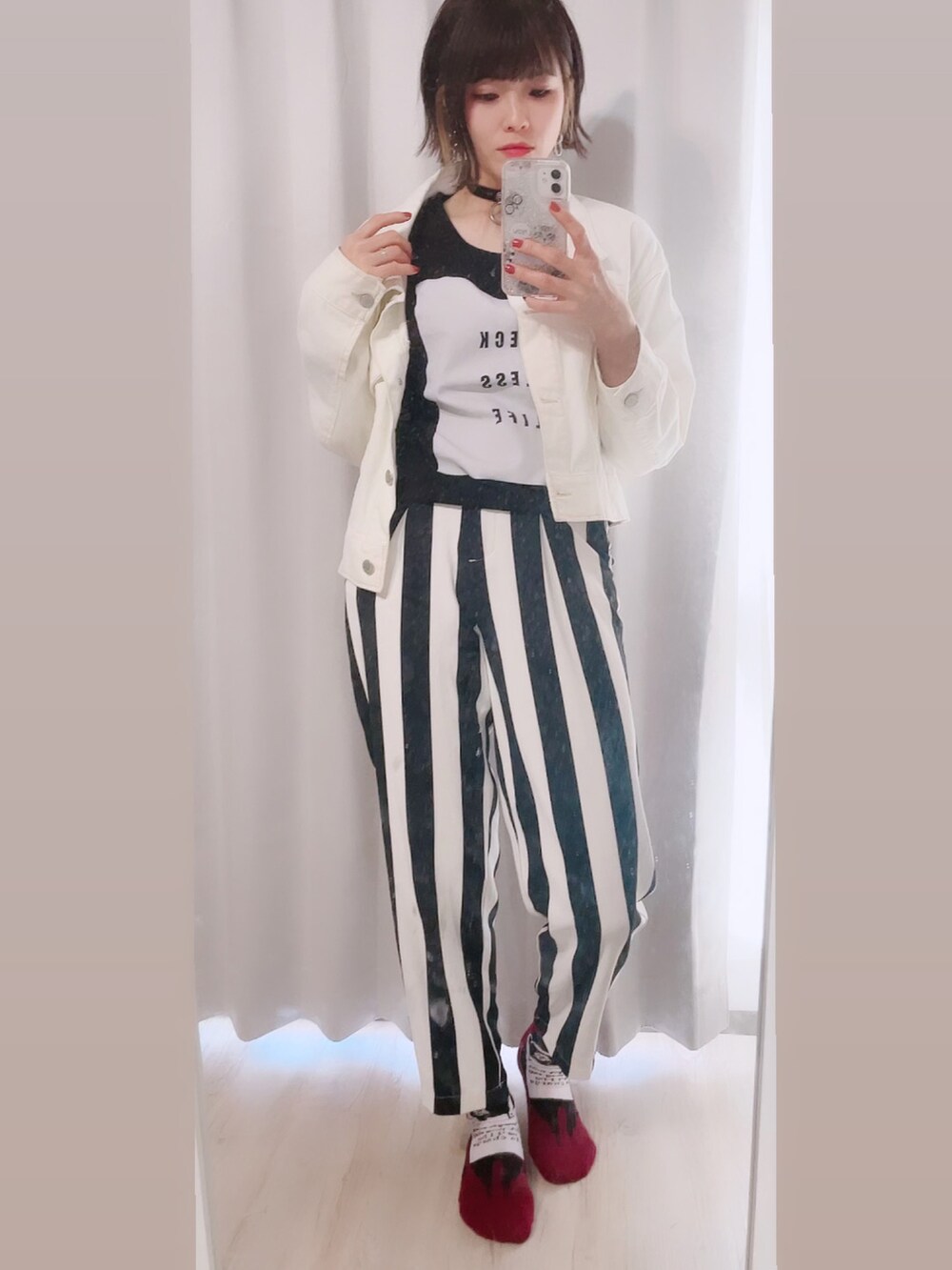 ブラック系のパンツ、ブラック系のブーツ、ホワイト系のデニムジャケットを着用したレディースの春コーディネートの3枚目の写真