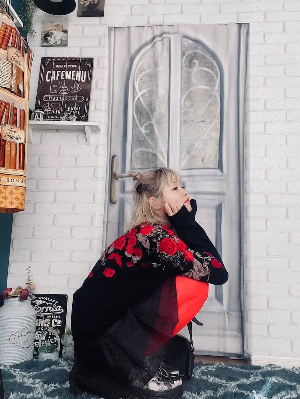 レッド系のニット/セーター、ブラック系のスカート、ブラック系のスニーカーを着用したレディースの秋コーディネートの3枚目の写真