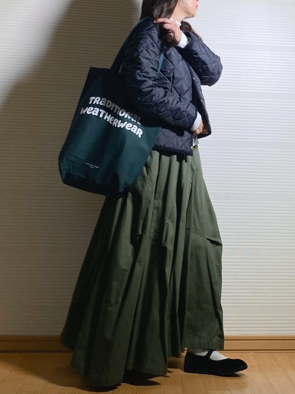 ブルー系のノーカラージャケット、グリーン系のトートバッグ、グリーン系のスカートを着用したレディースの秋コーディネートの2枚目の写真