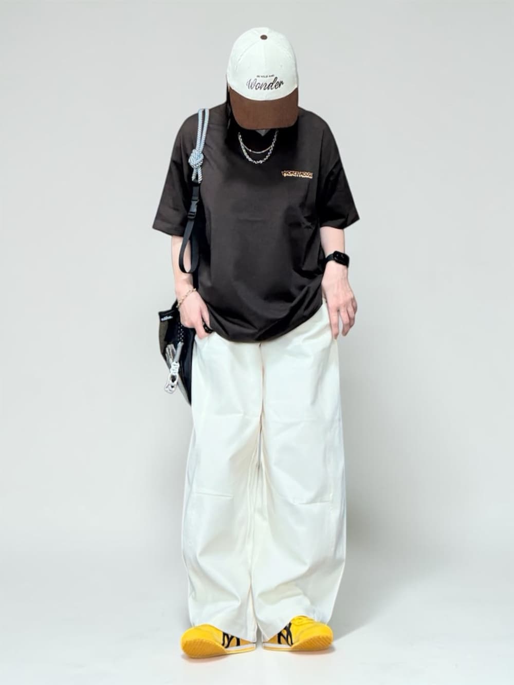 ブラウン系のTシャツ/カットソー、ホワイト系のその他パンツ、ブラック系のエコバッグ/サブバッグを着用したレディースの夏コーディネートの4枚目の写真