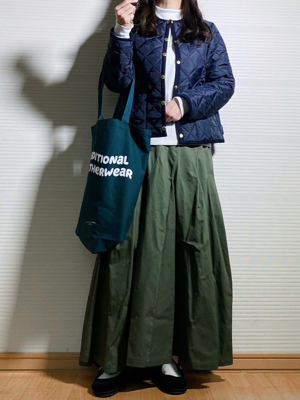 ブルー系のノーカラージャケット、グリーン系のトートバッグ、グリーン系のスカートを着用したレディースの秋コーディネートの3枚目の写真