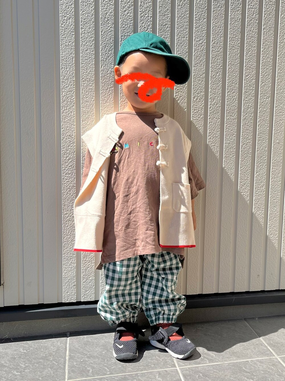 ホワイト系のベスト、ベージュ系のTシャツ/カットソー、グリーン系のパンツを着用したキッズの秋コーディネートの2枚目の写真