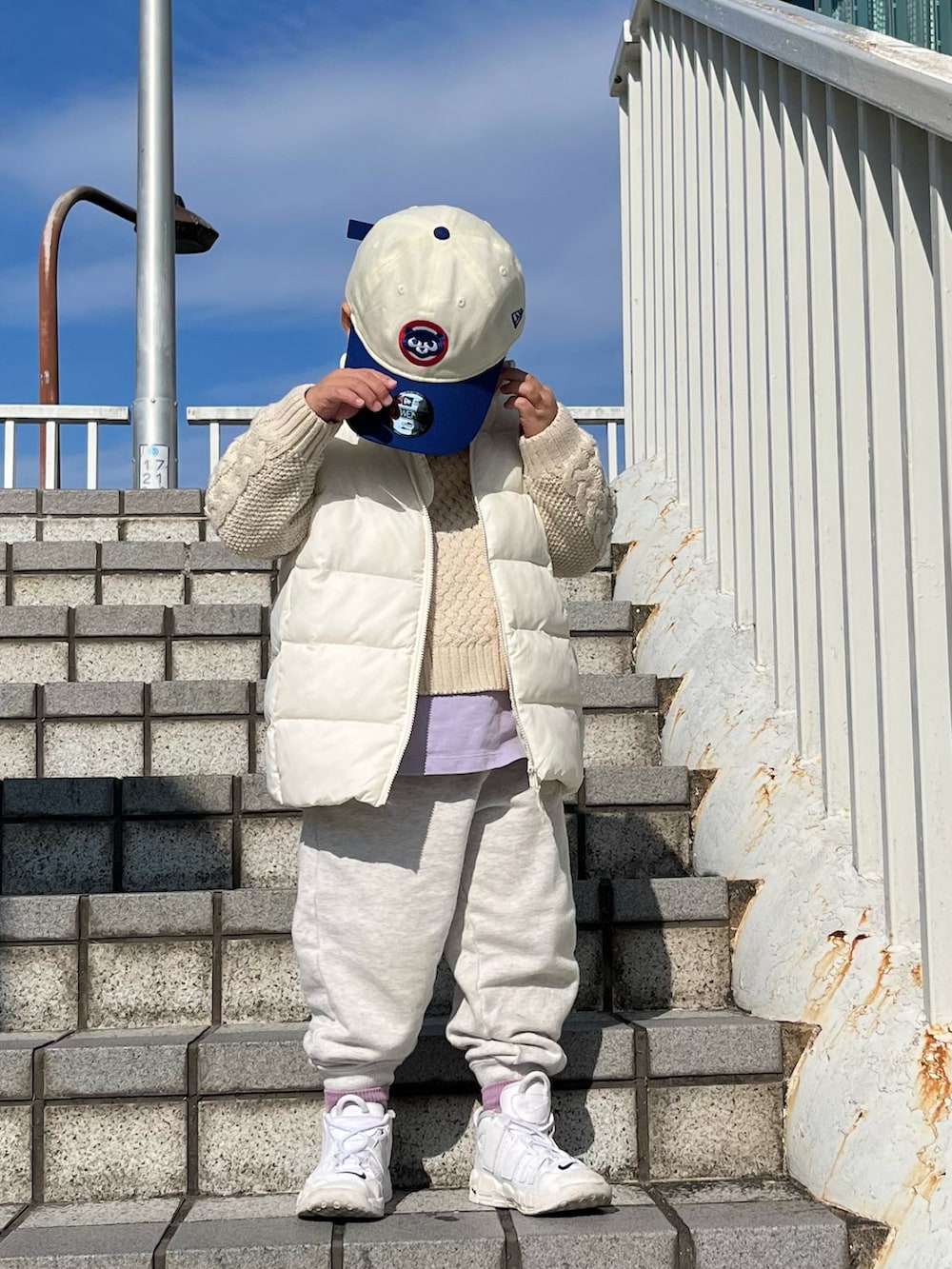 ホワイト系のニット/セーター、ブラック系のダウンベスト、ホワイト系のスウェットパンツを着用したレディースの冬コーディネートの2枚目の写真