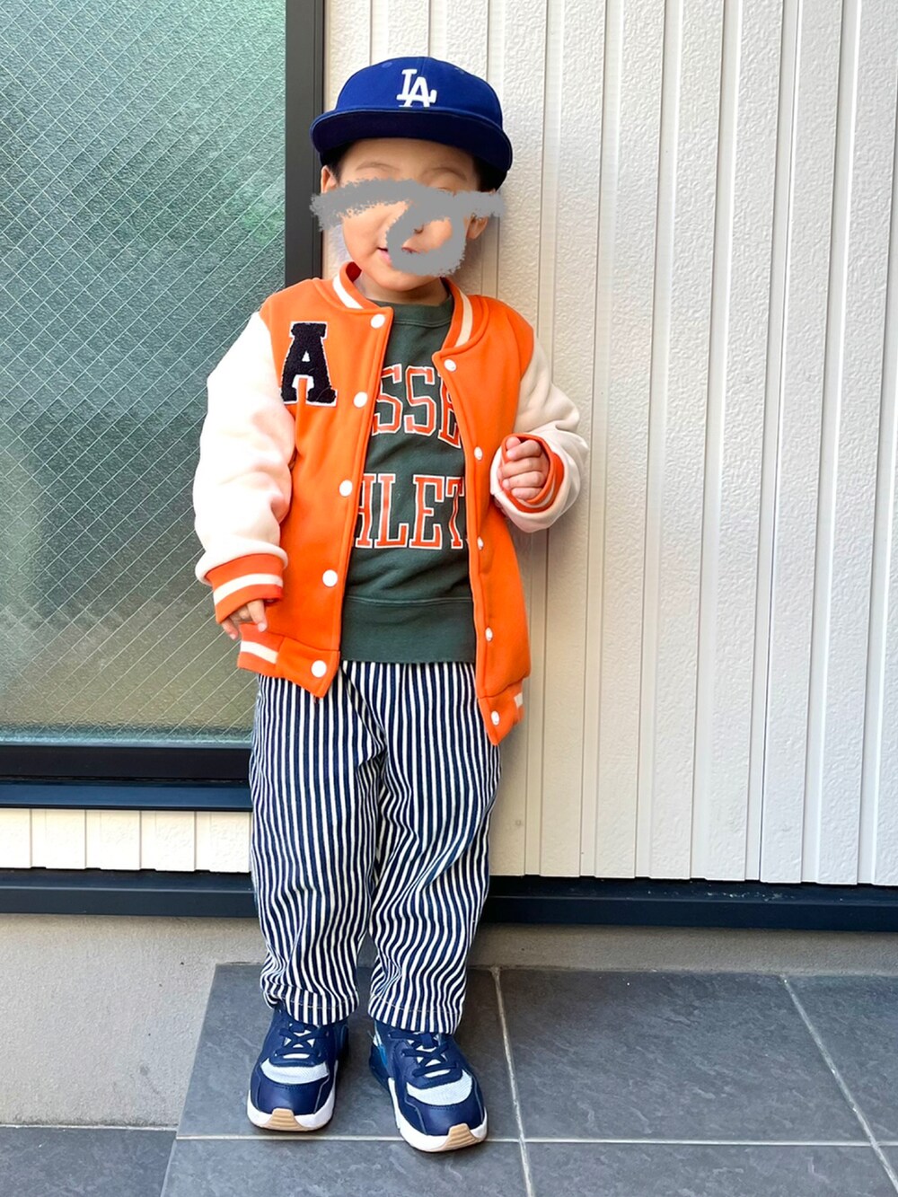 オレンジ系のスタジャン、グリーン系のスウェット、ブルー系のパンツを着用したキッズの冬コーディネートの2枚目の写真