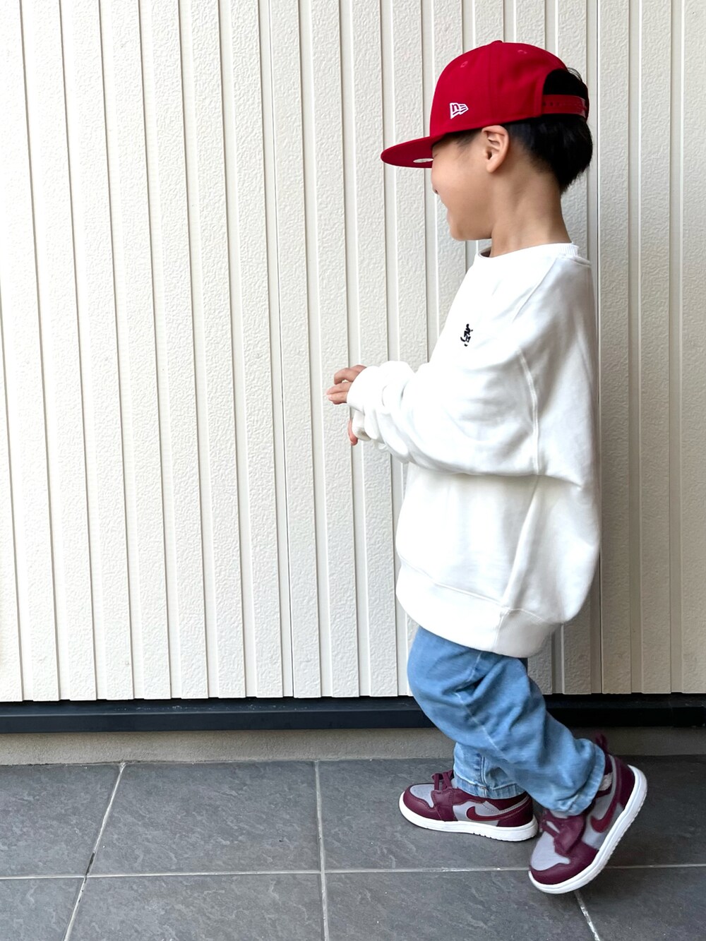 ホワイト系のスウェット、ブルー系のデニムパンツ、レッド系のスニーカーを着用したキッズの冬コーディネートの2枚目の写真