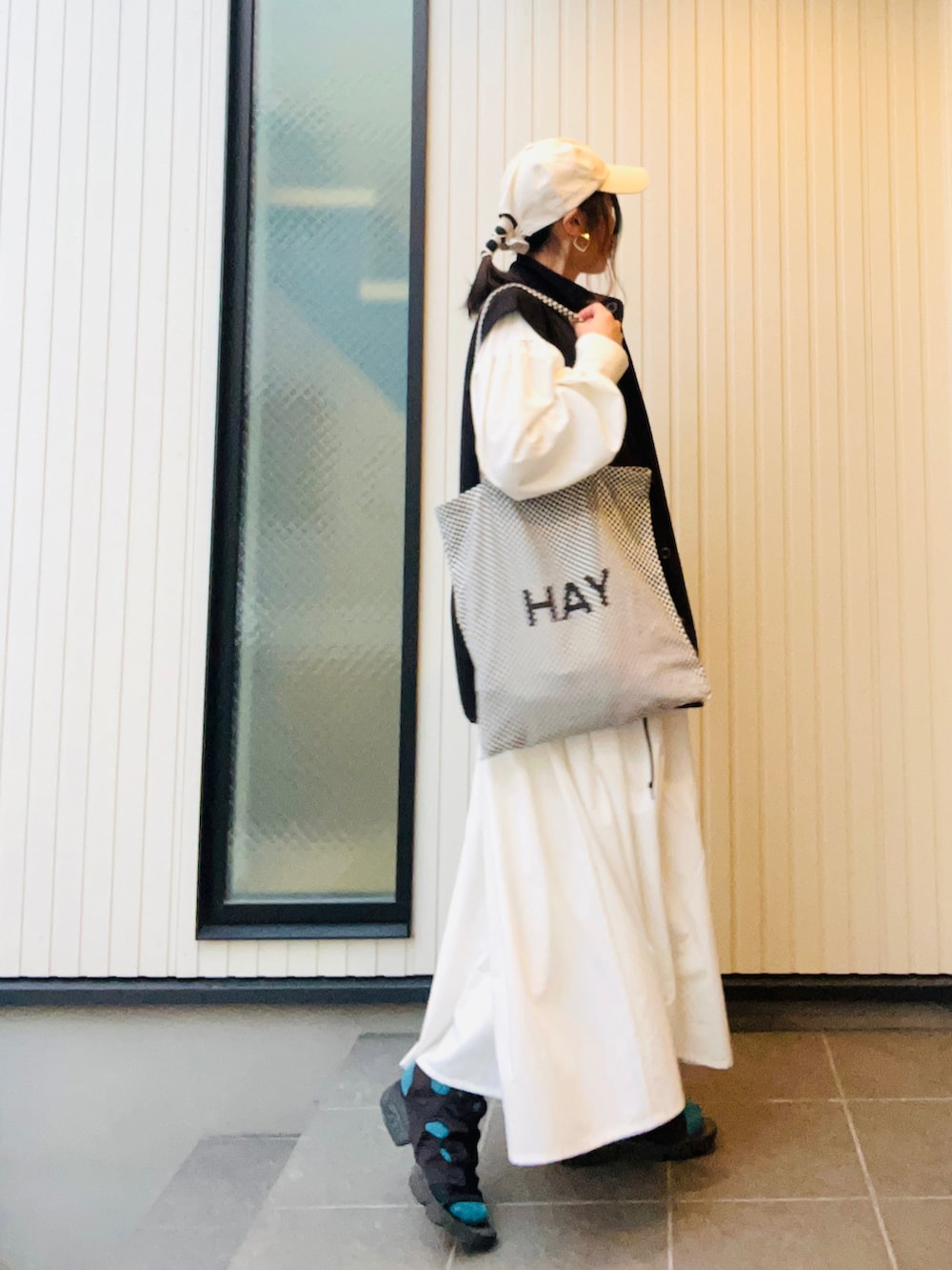 ホワイト系のワンピース、ブラック系のベスト、その他のトートバッグを着用したレディースの春コーディネートの2枚目の写真