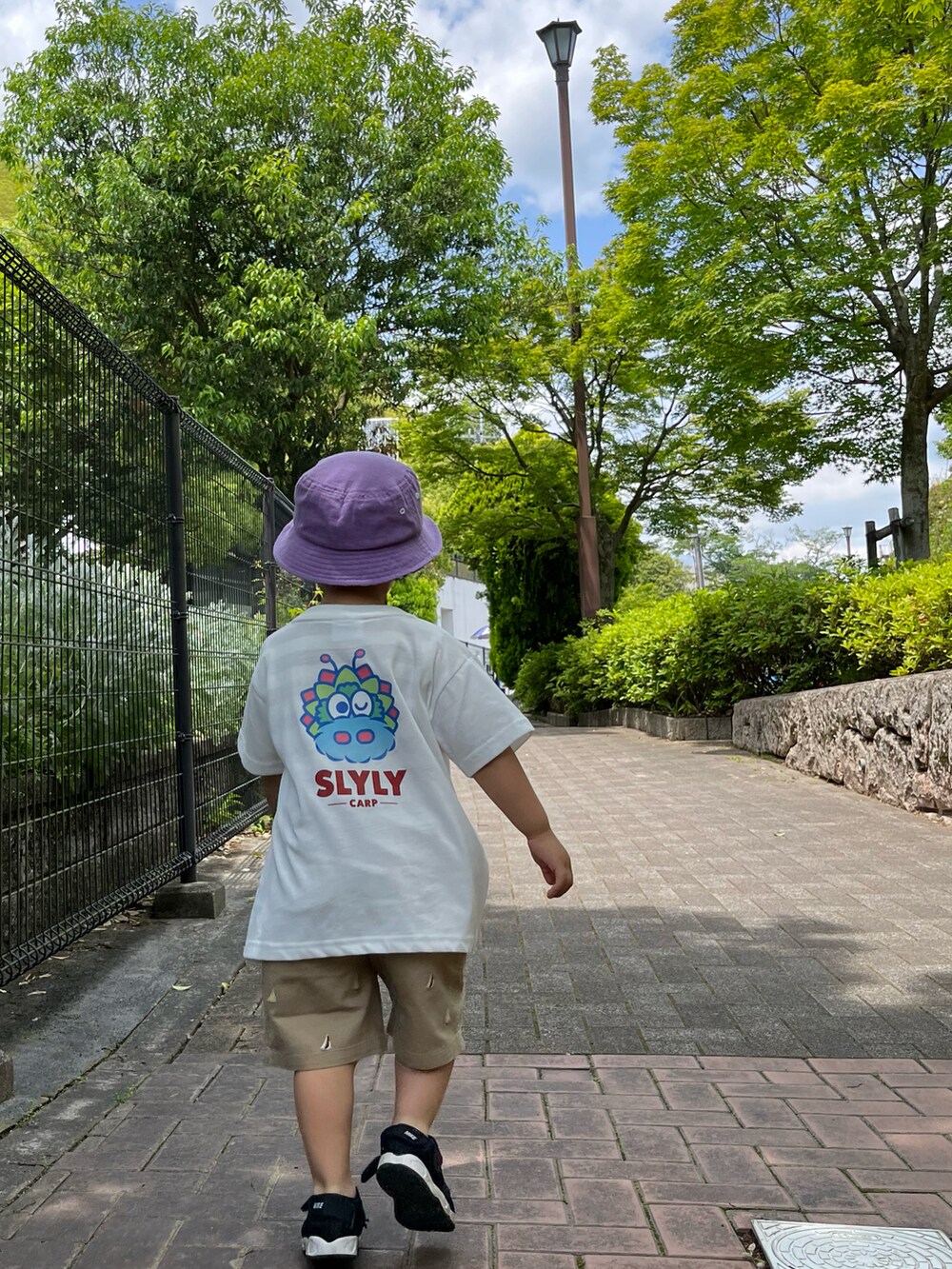 ホワイト系のTシャツ/カットソー、ベージュ系のチノパンツ、ブラック系のサンダルを着用したキッズの春コーディネートの2枚目の写真